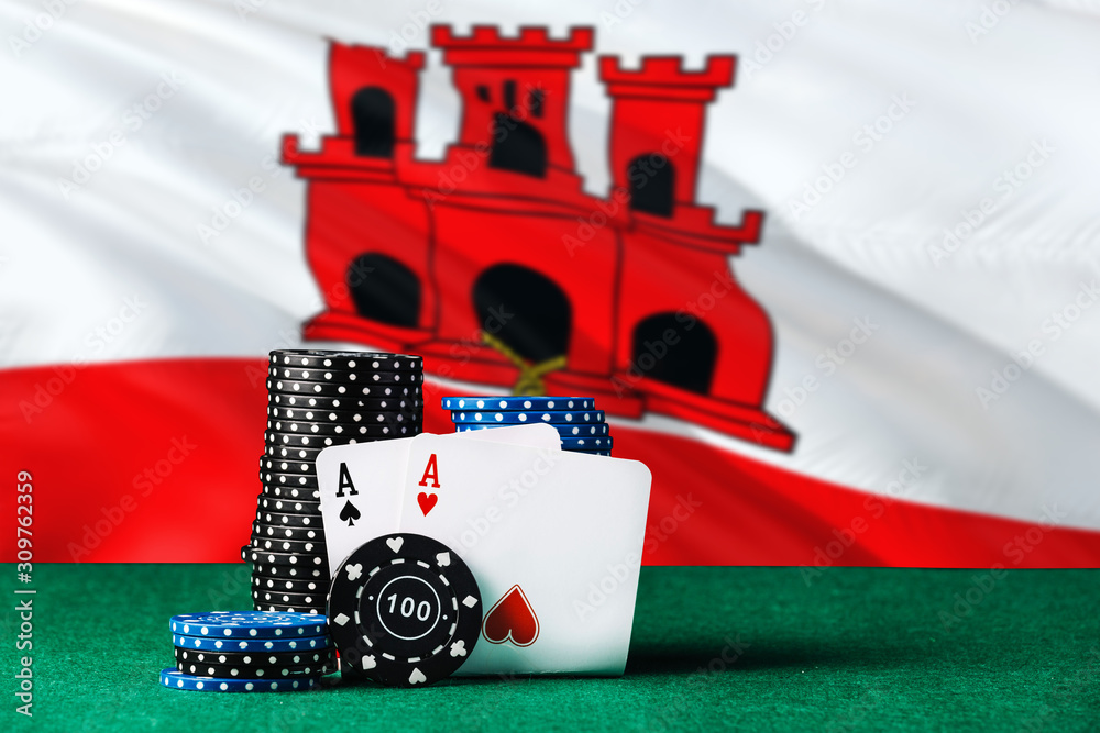 Gibraltar casino theme. Two ace in poker game, cards and black chips on green table with national flag background. Gambling and betting.