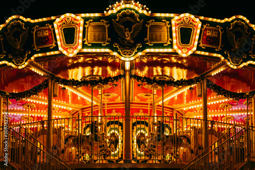 partial view of beautiful carousel with many light at night in theme park © Vlad