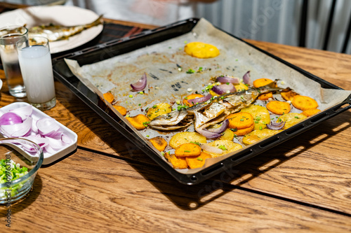 Baked Fish Bluefish with Sweet Potatoes on Oven Tray with Baking Paper Sheet / Lufer. photo