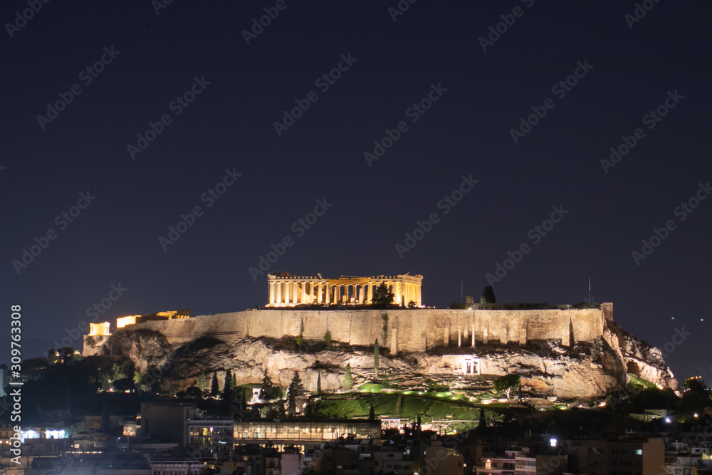 Night view of acropolis building on a hill with lights and beautiful scenery in Athens Greece