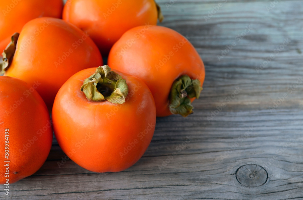 Fresh ripe organic Persimmon or Kaki fruit on old wooden table. Diospyros kaki.Healthy food vegetarian or raw diet concept.Copy space.Selective focus. Fresh ripe organic Persimmon or Kaki fruit on old wooden table. Diospyros kaki.Healthy food vegetarian or raw diet concept.Copy space.Selective focus.