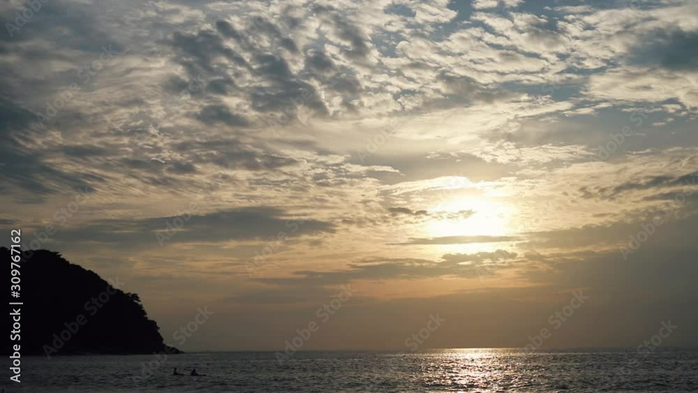 Panning from silhouette island to Sunset over the Yanui beach in Phuket with a lot of cloud in front of the sun, between island mountain on the ocean. Have people sailing mini boat at there Panning from silhouette island to Sunset over the Yanui beach in Phuket with a lot of cloud in front of the sun, between island mountain on the ocean. Have people sailing mini boat at there