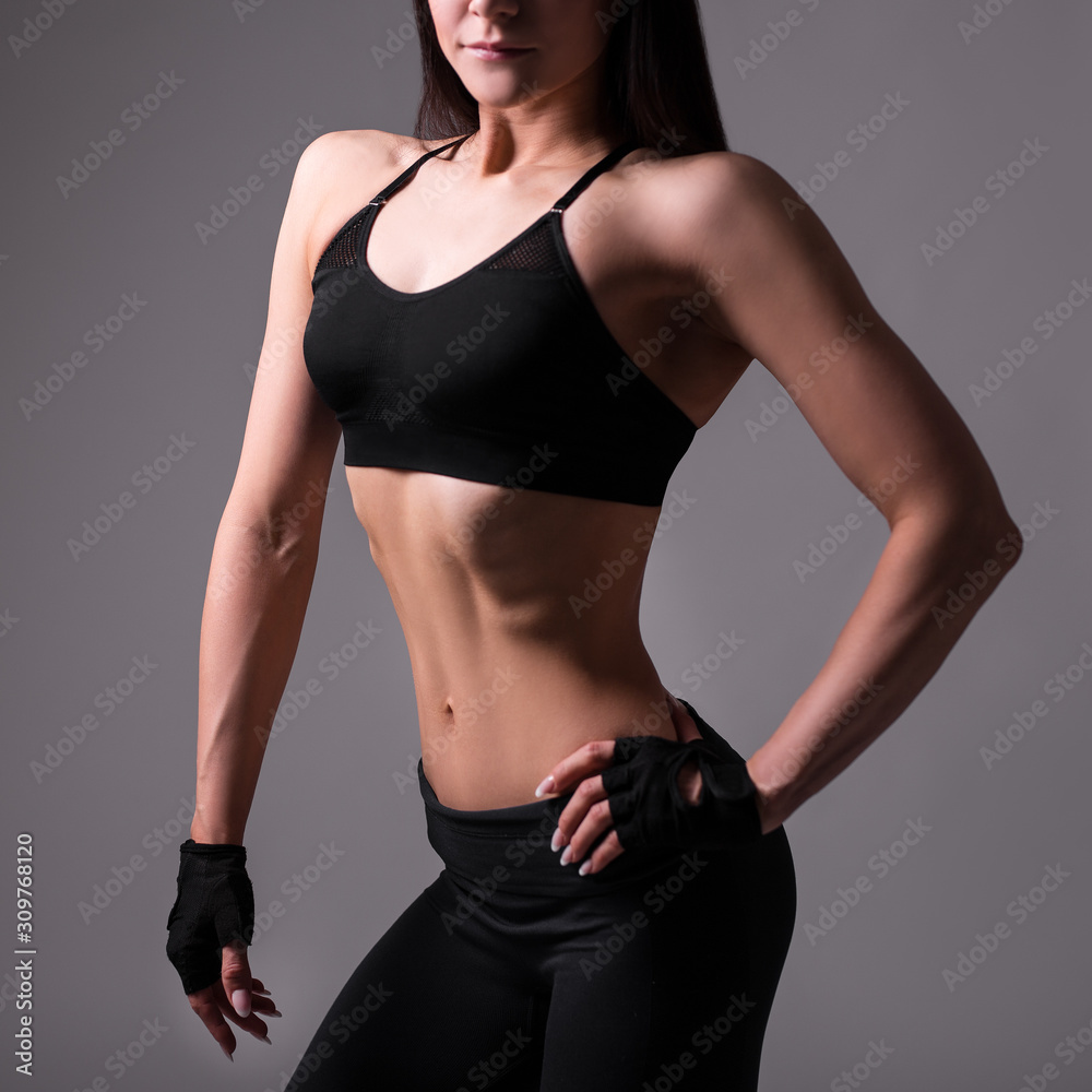 slim sporty muscular female body over gray background