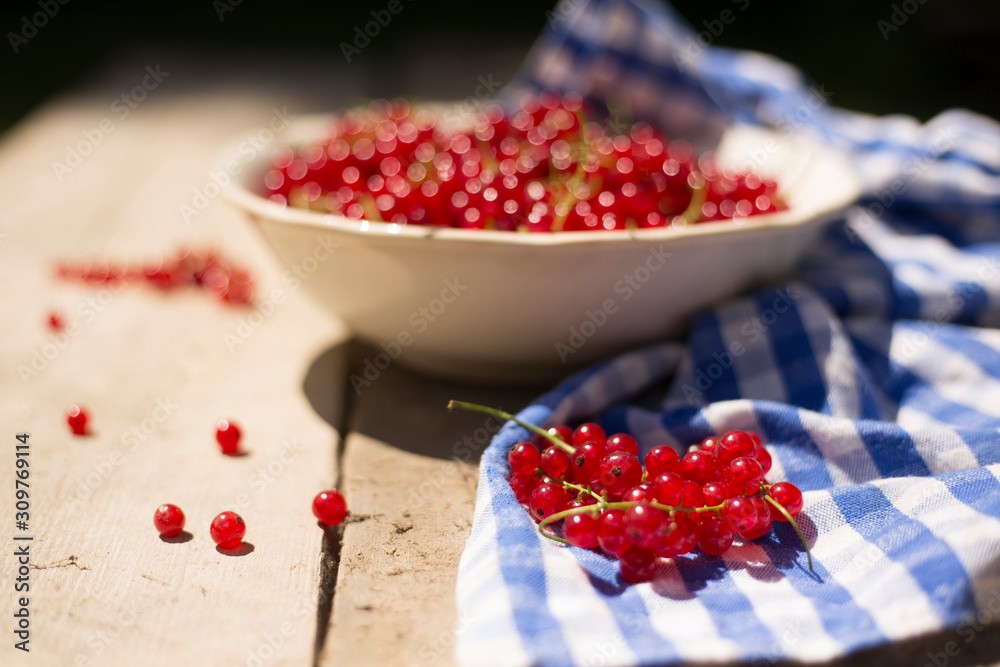 Detail on a bunch of red currant in a bowl on a wooden table