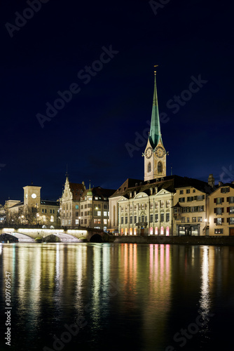 Münsterbrücke und Fraumünster bei Nacht, beleuchtetes Stadthaus und Zunft zur Meisen, Wasserspiegelung in der Limmat, Hochformat