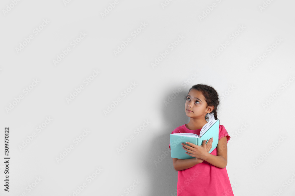 Cute little girl with book on light background, space for text Cute little girl with book on light background, space for text