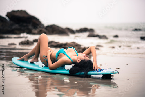 Woman Lying On Surfboard At Beach Against Sky