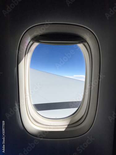 Airplane window with blue sky background
