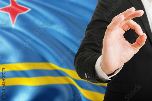 Aruba acceptance concept. Elegant businessman is showing ok sign with hand on national flag background.