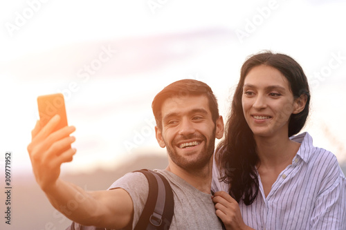 Couple taking selfie photo with smart phone hiking on mountain.