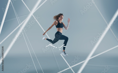 Female athlete running and jumping. Side view shot of healthy woman working out against hi tech background. 
