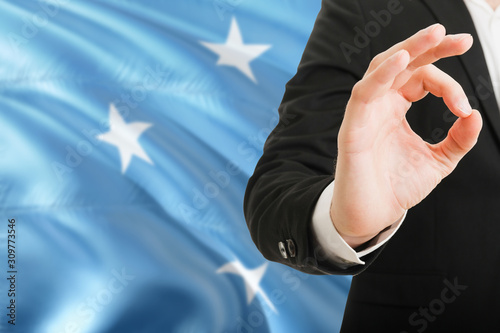 Micronesia acceptance concept. Elegant businessman is showing ok sign with hand on national flag background.