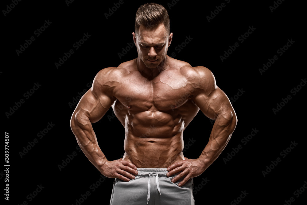 Muscular man showing muscles isolated on the black background. Strong male naked torso abs