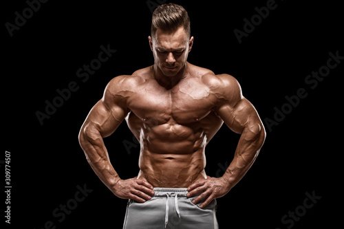 Muscular man showing muscles isolated on the black background. Strong male naked torso abs