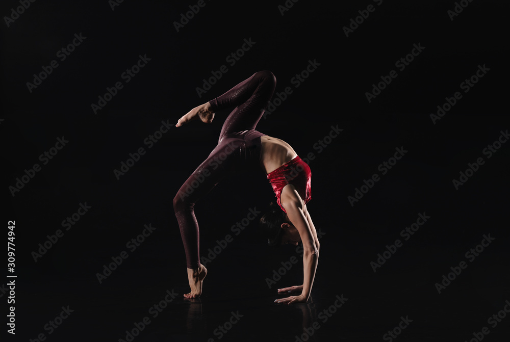 Young woman performing acrobatic element on stage indoors. Space for text