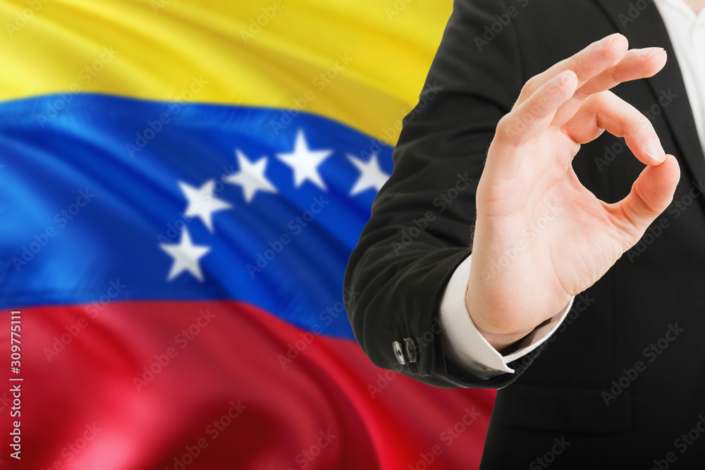 Fototapeta premium Venezuela acceptance concept. Elegant businessman is showing ok sign with hand on national flag background.