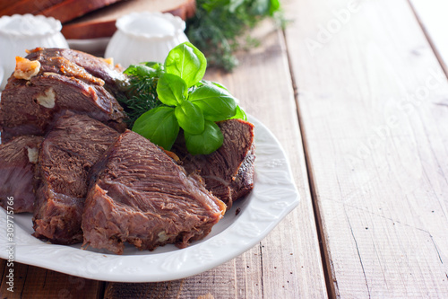 sliced baked beef fillet on a white dish with fresh herbs, horizontal, copy space