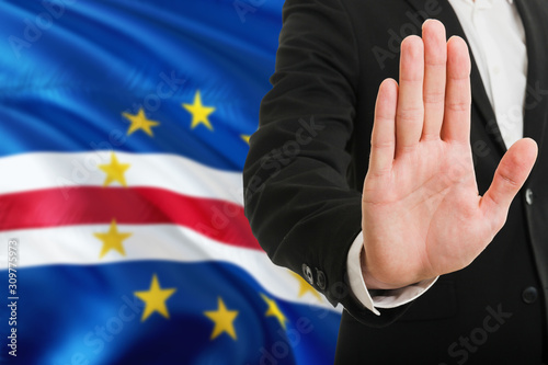Cape Verde rejection concept. Elegant businessman is showing stop sign with hand on national flag background.