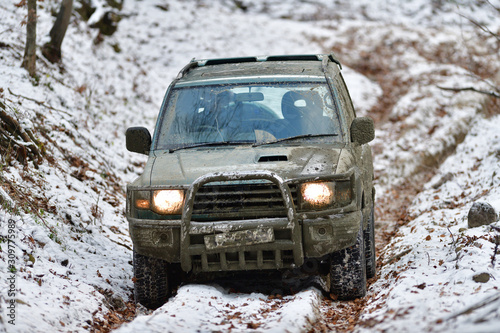 Dirty off-road car in forest on snow and mud