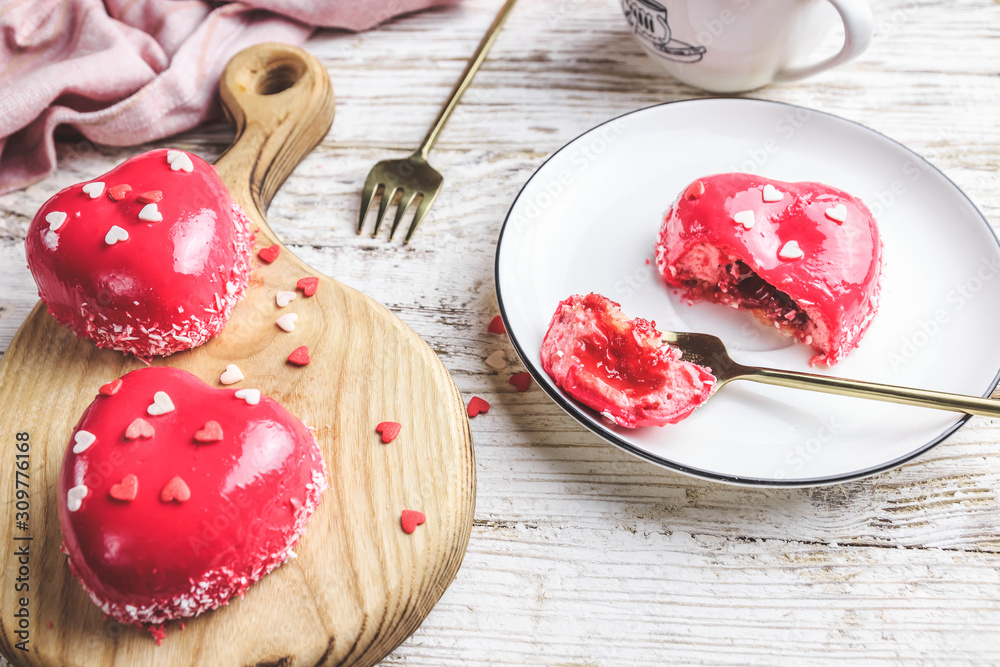 Pink mousse cakes in the shape of a heart decorated with mini hearts on a white rustic background. Heart shaped cakes for Valentine's Day or Mother's day. Selective focus. Pink mousse cakes in the shape of a heart decorated with mini hearts on a white rustic background. Heart shaped cakes for Valentine's Day or Mother's day. Selective focus.