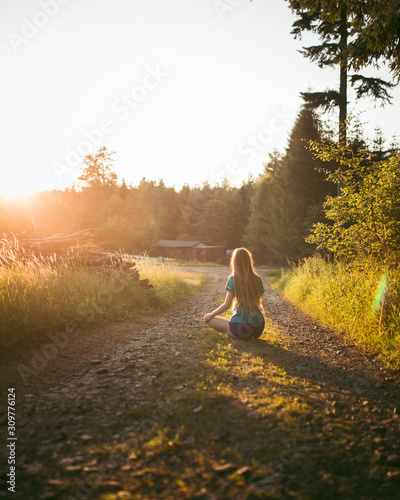 Young sporty woman sitting early morningon the forest road photo