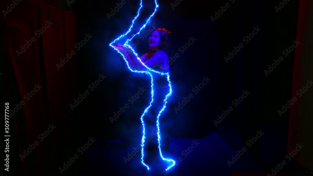 A female devil in an electric halo laughs and sways. A female devil in an electric halo laughs and sways.