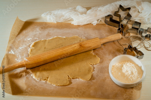 Rolled raw dough on a table with a towel and a rolling pin for cookies.