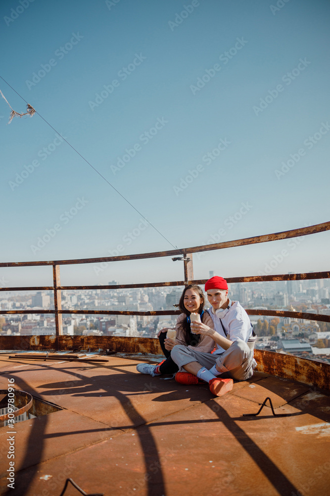 Lovely couple sitting on roof with food in hands Lovely couple sitting on roof with food in hands