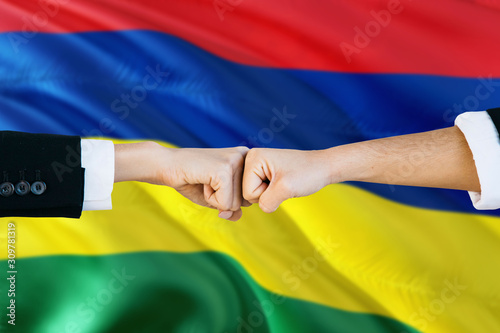 Mauritius agreement concept. Man and woman fist bumping on national flag to show cooperation. Peace and teamwork theme.