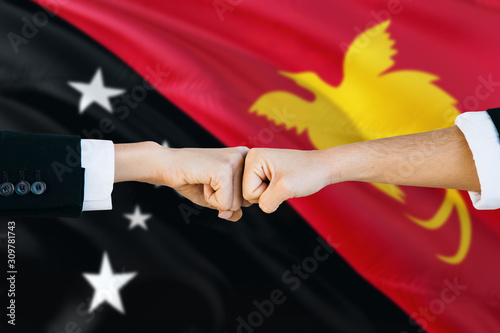 Papua New Guinea agreement concept. Man and woman fist bumping on national flag to show cooperation. Peace and teamwork theme.