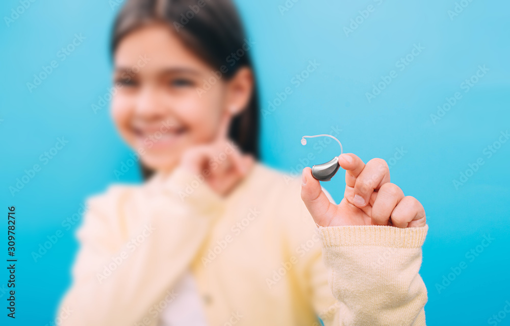 advertising hearing aid for children, a mixed race child shows a hearing aid. Children's hearing treatment advertising hearing aid for children, a mixed race child shows a hearing aid. Children's hearing treatment