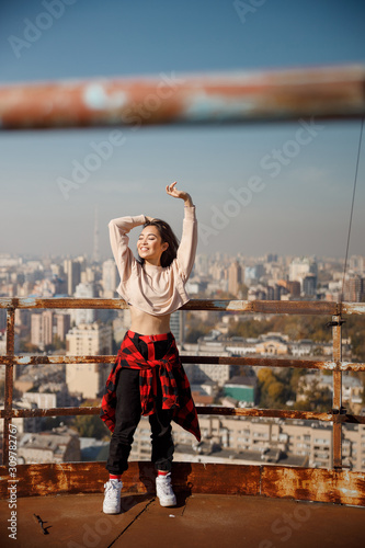 Smiling attractive girl standing with closed eyes on roof