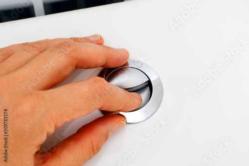 Close-up of woman hand pressing button for flushing.