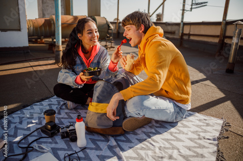 Lovely couple sitting on the bedspread on the roof