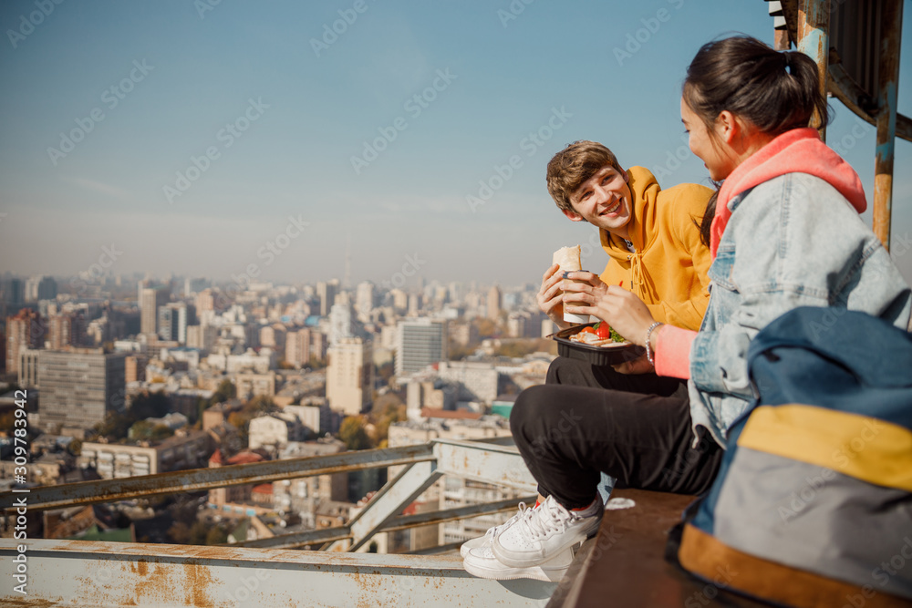 Happy boyfriend looking at girlfriend having lunch on roof