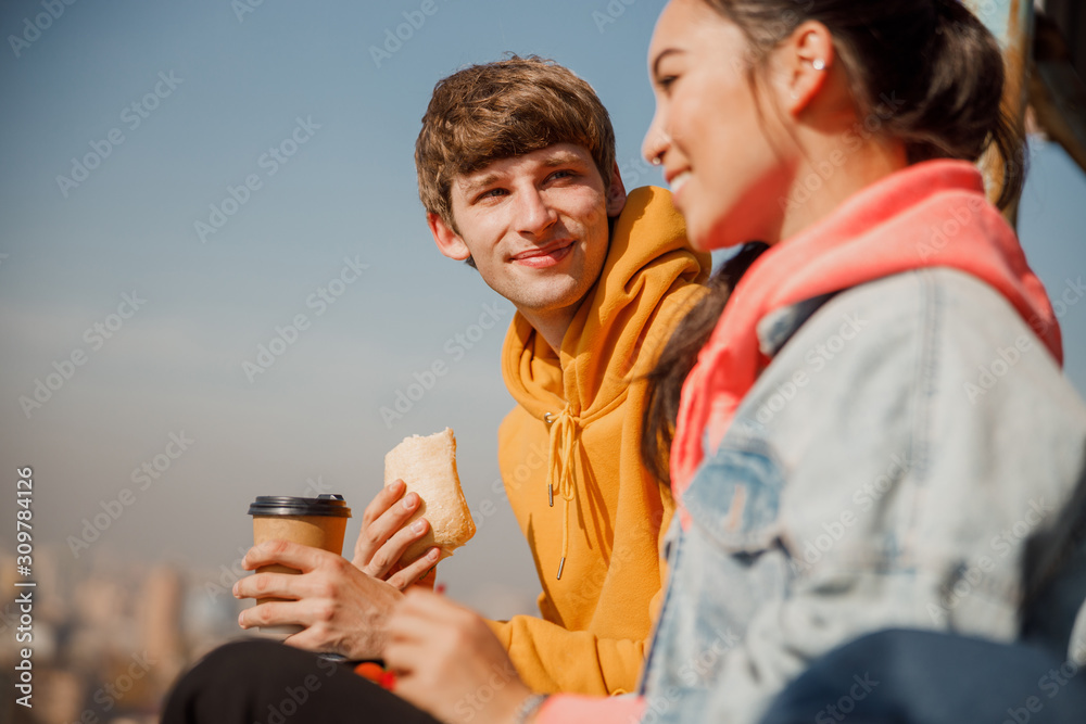 Happy young guy holding sandwich on the roof Happy young guy holding sandwich on the roof