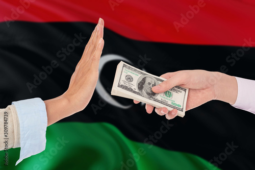 Libya bribery refusing. Closeup of female hands extending a pile of dollar bills to the male hands gesturing as if rejecting the money.