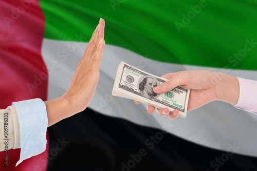 United Arab Emirates bribery refusing. Closeup of female hands extending a pile of dollar bills to the male hands gesturing as if rejecting the money.