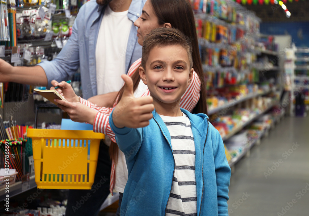 Obraz premium Little boy with parents choosing school stationery in supermarket
