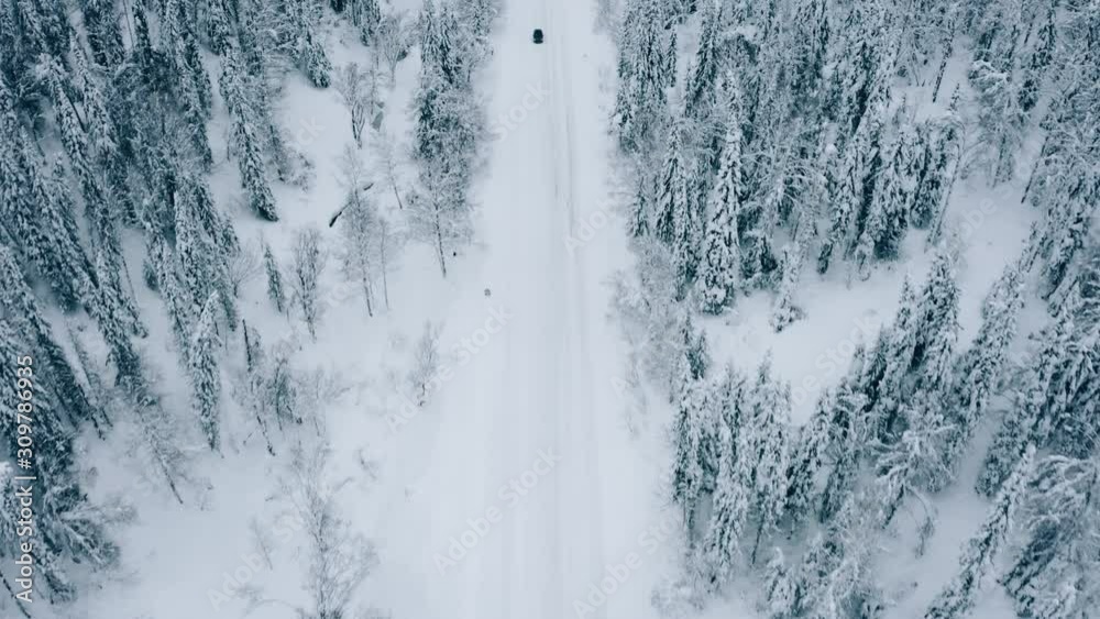 Top view of a car on a winter highway among a snowy coniferous forest Top view of a car on a winter highway among a snowy coniferous forest