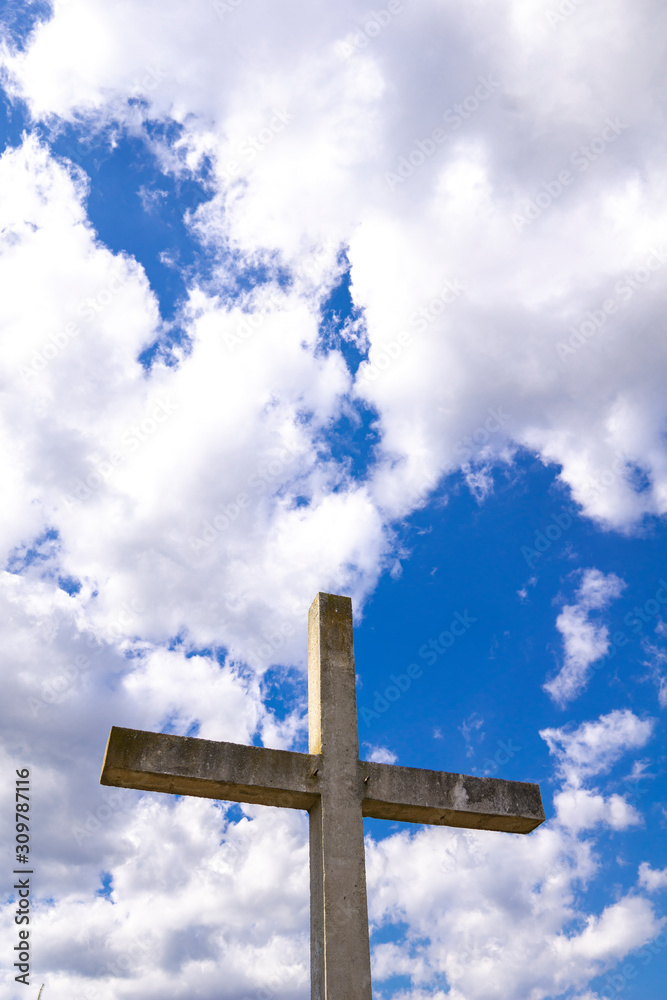 Stone cross behind clouds against blue sky