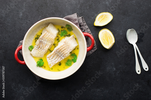 Steamed cod fillet butter-lemon sauce with herbs in the oven. Top view. In a baking dish. Healthy eating