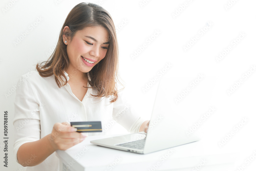 Asian woman using credit card shopping online with laptop computer on white background Asian woman using credit card shopping online with laptop computer on white background