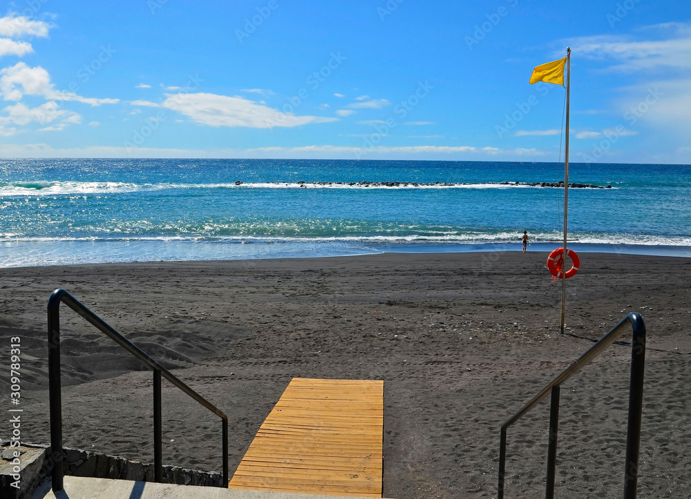 Obraz premium View of Playa del Duque beach with yellow flag on the south of Tenerife,Canary Islands,Spain.Travel or vacation concept.