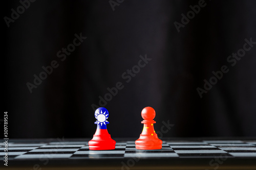 China and Taiwan flag print screen on pawn chess with black background. Now both countries have economic and patriotic conflict.