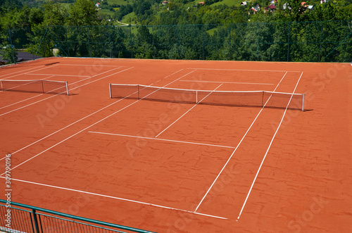 Empty outdoor tennis court in a lush surrounding on a sunny day © branislav