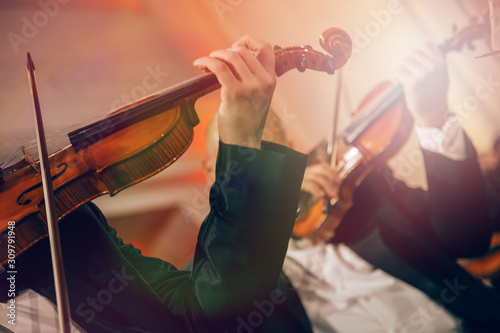 Symphony orchestra on stage, hands playing violin