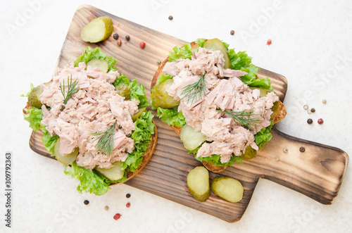 Obraz na płótnie Flat lay view at homemade tuna salad sandwiches on cutting board with pickles aside w salonie