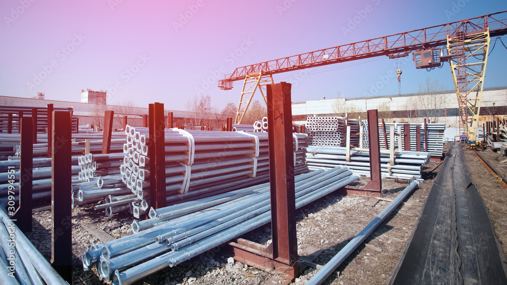 Metal warehouse outdoor of lighting poles. Storage of metal galvanized faceted pipes with flange. Metal warehouse outdoor of lighting poles. Storage of metal galvanized faceted pipes with flange.