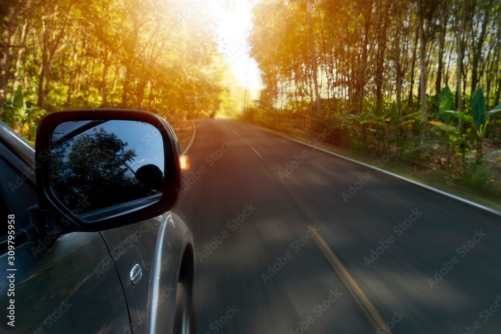 Speed of car travel on the asphalt road heading to nature of rubber tree forest. with orange light.